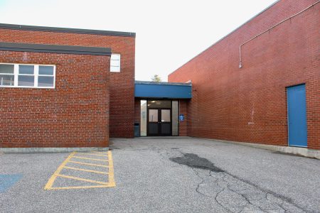 The back entrance of a brick building with handicap-accessible parking and a double-door entrance.